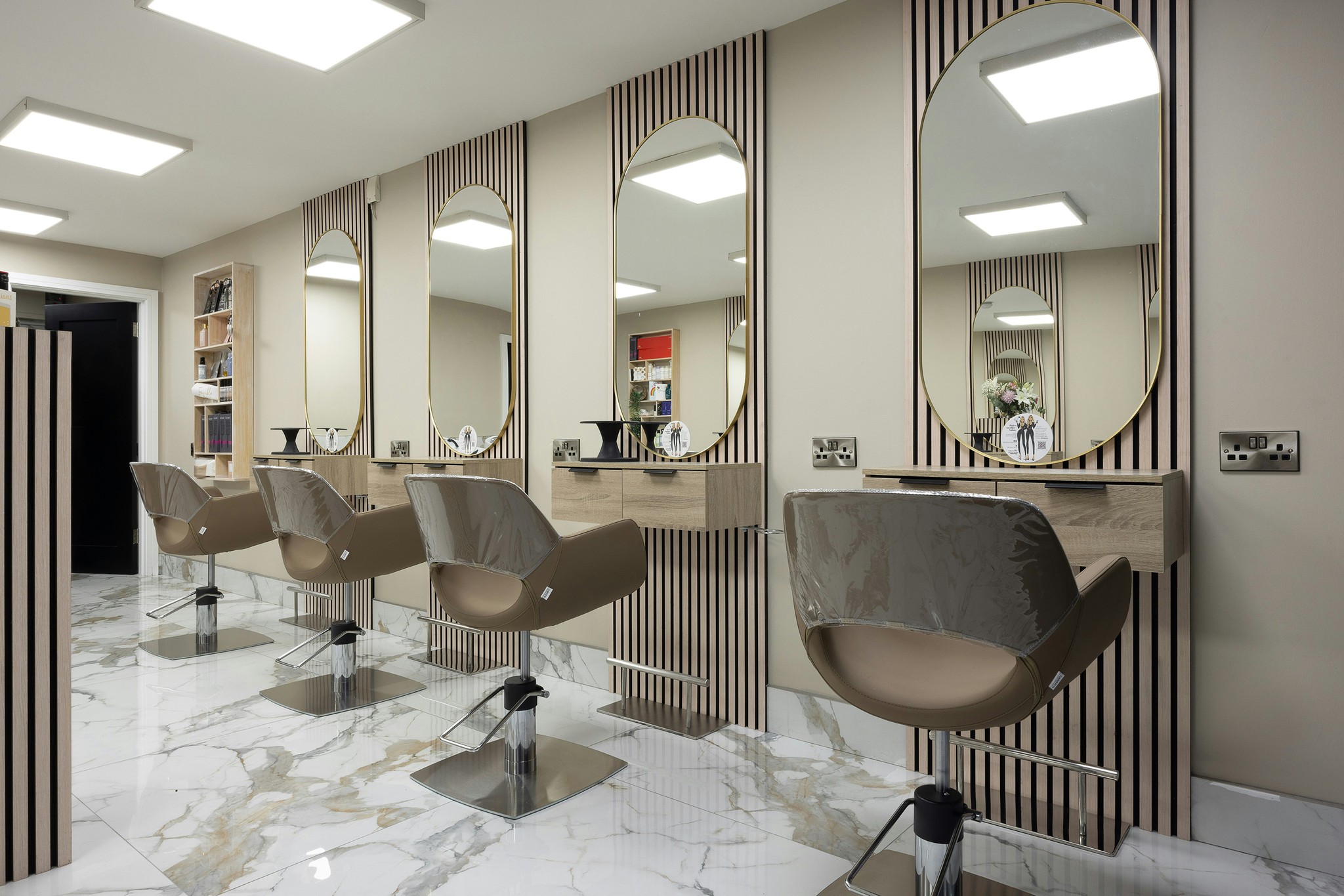 Sala principal do salão, com espelhos ovais e cadeiras de styling